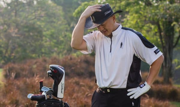 Tony Meechai on the course with his bag, in his signature black hat