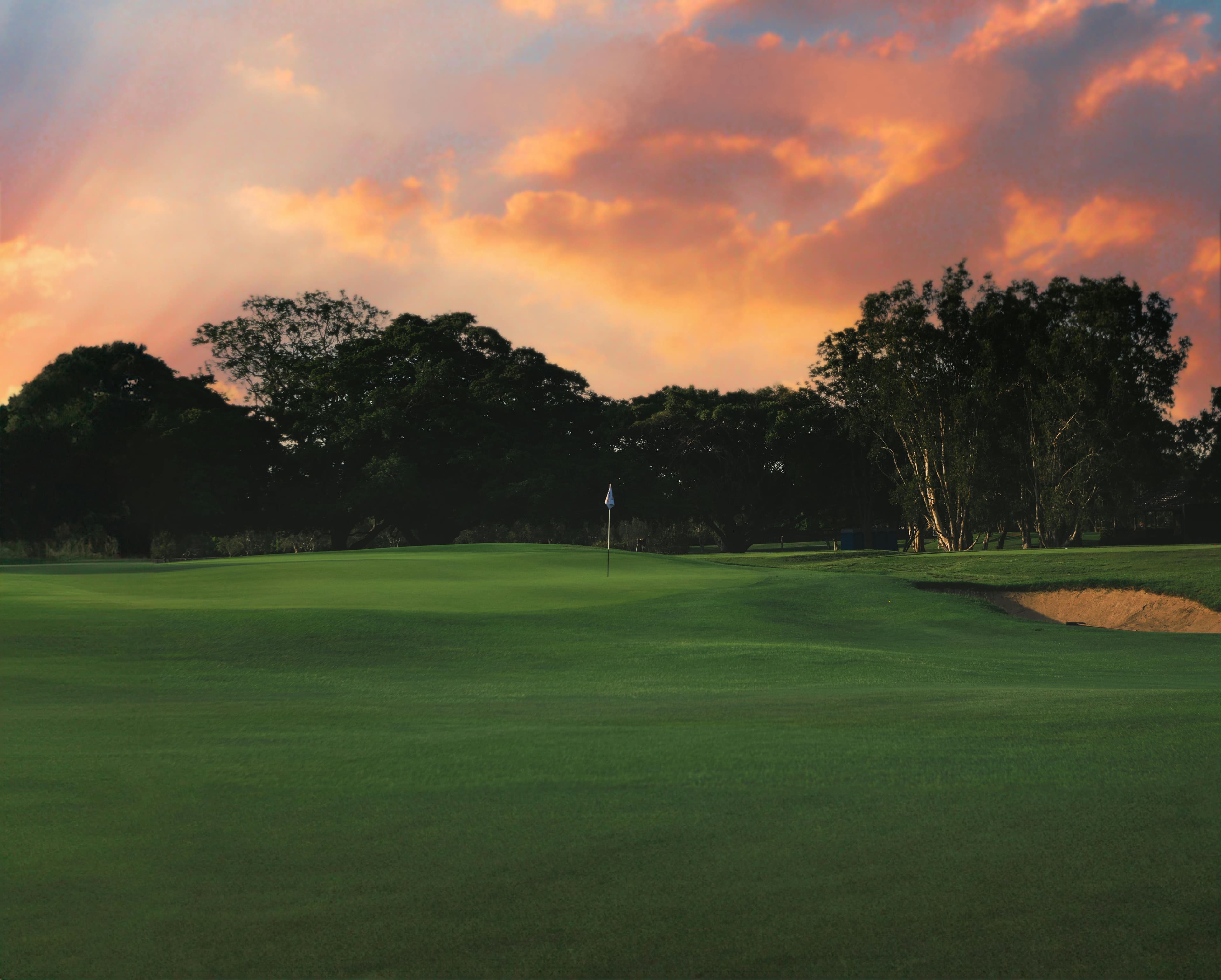 Dramatic sunset over a lush green golf course